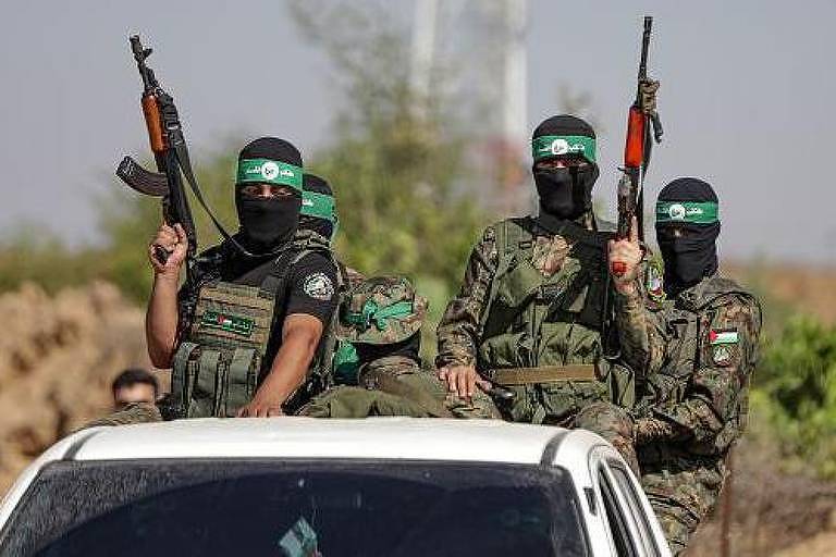 Combatentes palestinos da ala militar do Hamas, mascarados, armados e em cima de carro branco
