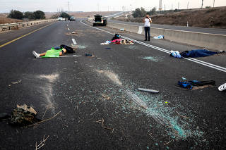 A man takes a photo of dead people strewn across a road following a mass-infiltration by Hamas gunmen from the Gaza Strip, in the Sderot area, southern Israel