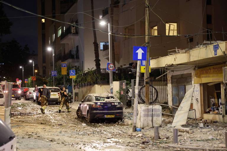 Forças de segurança de Israel caminham em meio a destroços em Tel Aviv