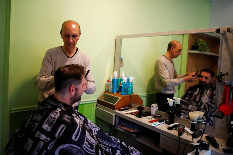 Ruben Galante, 67, corta o cabelo do seu cliente, Luciano Munoz, 46, em sua barbearia, em Buenos Aires