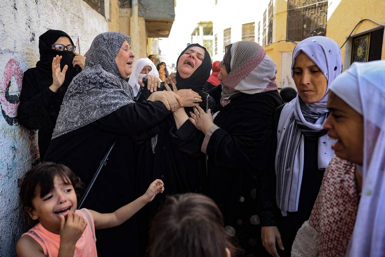 Mulheres choram durante o funeral de membros da família Abu Quta que foram mortos em ataques israelenses na cidade palestina de Rafah, ao sul da Faixa de Gaza