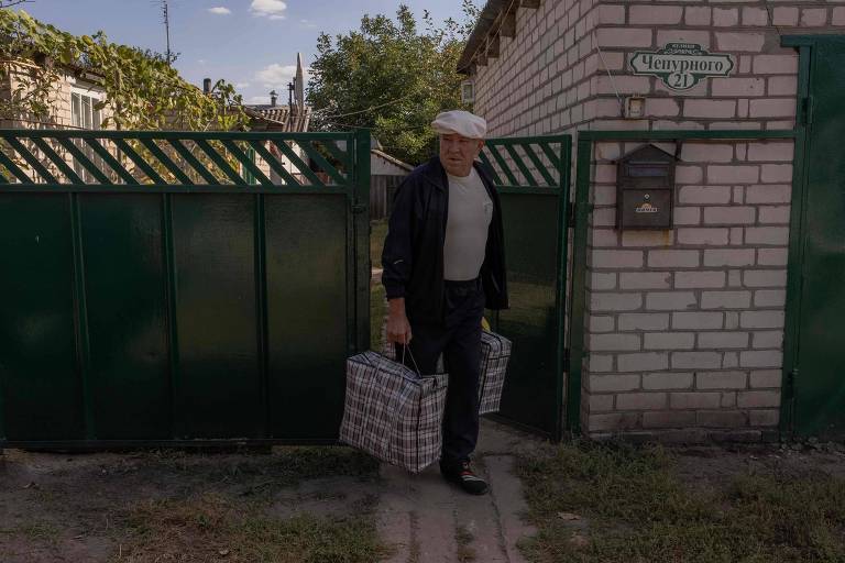 Sergii, 71, carrega sacolas enquanto deixa sua casa na cidade de Boguslavka, em Kharkiv, região em disputa pelos russos