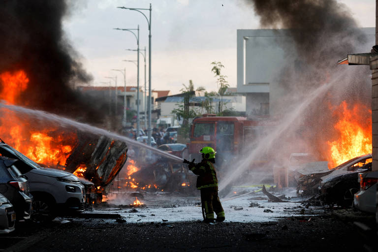 Um membro da equipe de emergência trabalha para extinguir o incêndio após o lançamento de foguetes da Faixa de Gaza, visto da cidade de Ashkelon, Israel