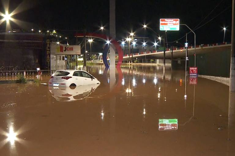 Carro parcialmente submerso em rua de Franco da Rocha
