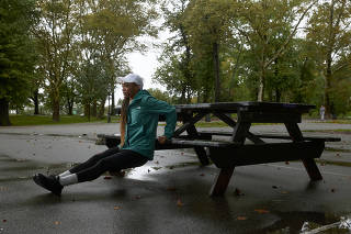A woman exercises in a park as it rains in New York, on Sept. 30, 2023. (Nicholas Sansone/The New York Times)