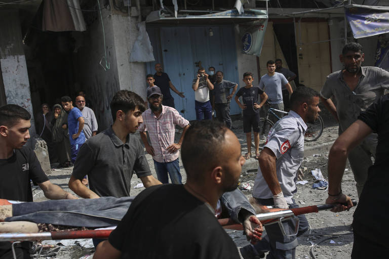 Corpo resgatado entre os escombros da mesquita de Soussi após ataque aéreo de Israel no campo de refugiados de Shati, na Faixa de Gaza, é carregado por moradores locais
