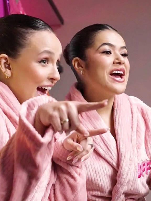 duas adolescentes brancas sorriem vestindo roupão rosa