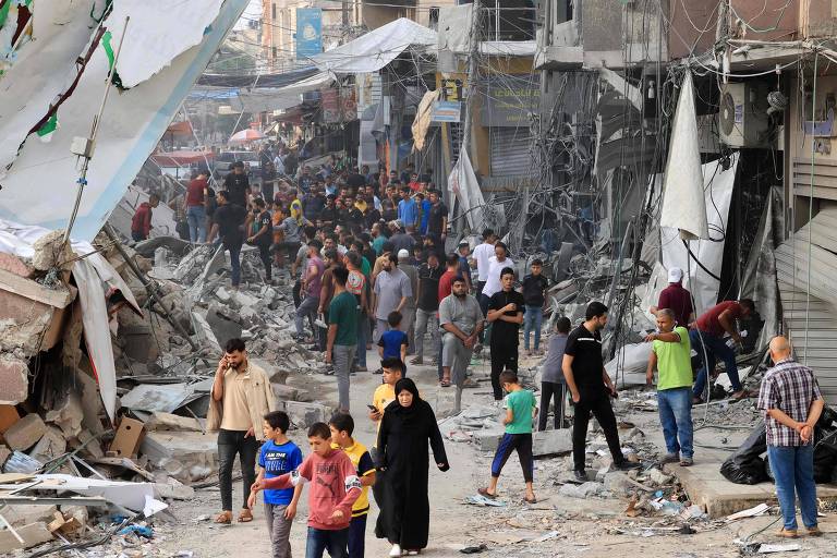 Palestinos andam em meio a escombros na cidade de Khan Yunis, no sul da Faixa de Gaza