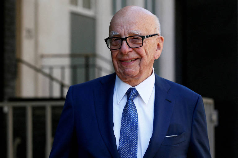 Rupert Murdoch sorri ao deixar sua casa em Londres