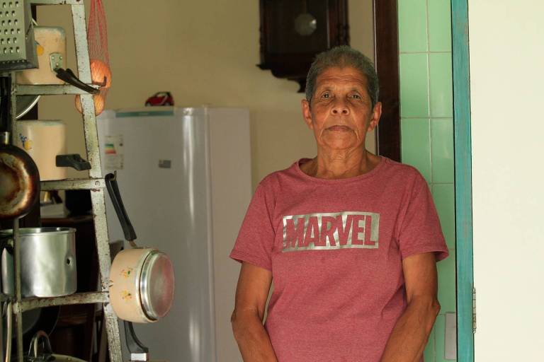 Senhora de 75 anos posa para foto com camiseta da Marvel. Ela tem cabelo curto e está séria, olhando para a foto