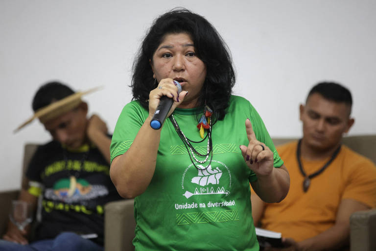 Mulher com camiseta verde fala ao microfone