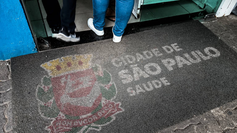 Tapete de fundo cinza com o logotipo de Prefeitura do lado esquerdo e os dizeres: Cidade de São Paulo Saúde, do lado direito