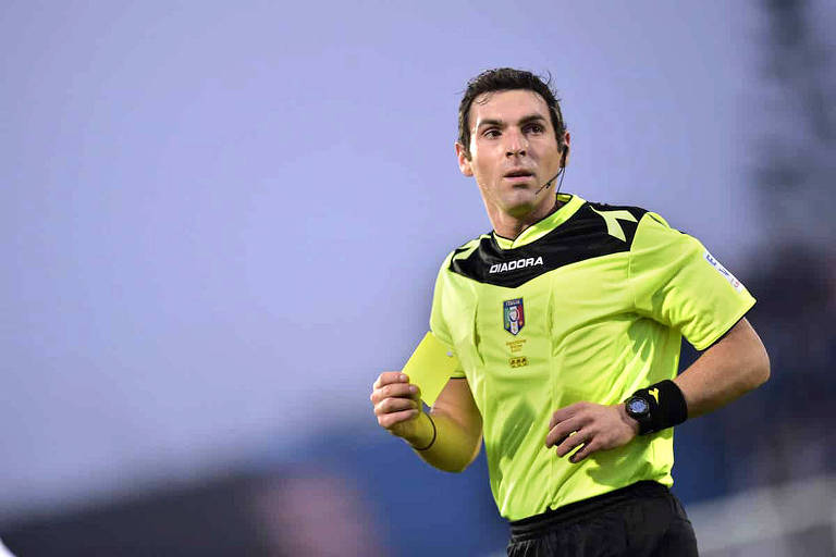 Usando camisa amarela, o árbitro italiano Juan Luca Sacchi corre durante partida de futebol