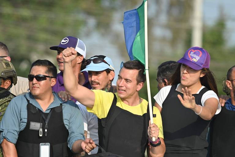 Daniel Noboa (centro), candidato à Presidência do Equador, durante comício final antes do segundo turno das eleições; ele e pessoas ao seu redor estão usando coletes à prova de balas