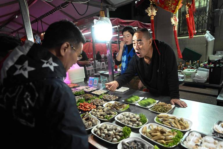 Comerciante negocia com cliente em mercado de rua na cidade de Dandong, na China