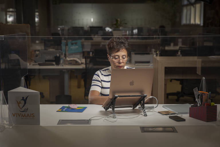 Mulher está sozinha mexendo no computador em um escritório