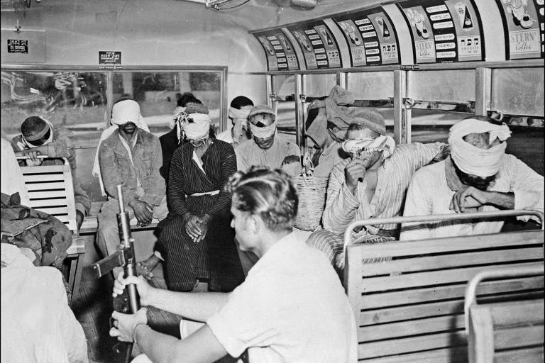 Em 25 de julho de 1948, soldado israelense, segurando metralhadora de fabricação britânica, acompanha grupo de prisioneiros árabes vendados em um ônibus em Jerusalém durante o primeiro conflito árabe-israelense