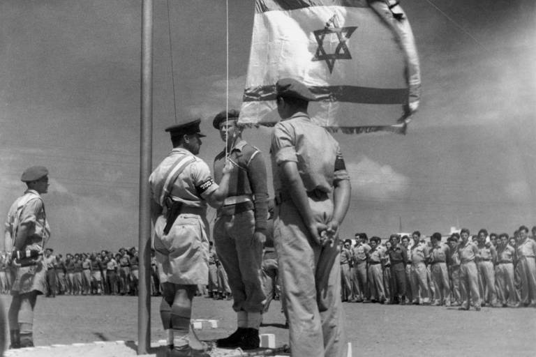 Oficial israelense hasteia a bandeira pela primeira vez durante a celebração do nascimento do país， em 8 de junho de 1948 
