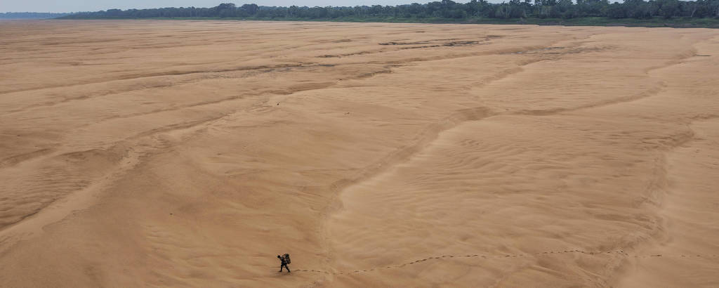 Pescador atravessa caminhando o leito seco do rio Solimões 