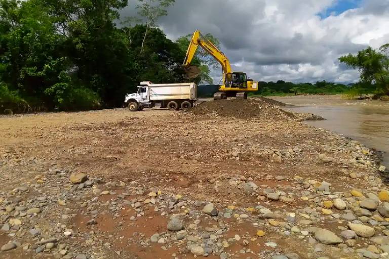 Caminhão e escavadeira na beira de um rio