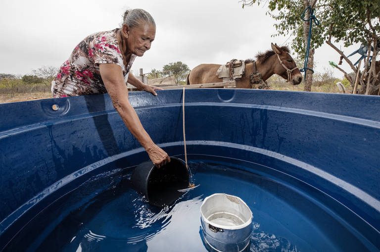 Maria de Fátima Jesus dos Santos, 68, pega água de sua caixa de água no assentamento Salinas, no sertão de Alagoas. O contraste entre áreas abastadas de equipamentos contra a seca e outras preteridas em razão do avanço das emendas parlamentares é tema de um minidocumentário lançado pela TV Folha que mostra que, enquanto pessoas andam horas para pegar água em regiões de baixa influência de emendas, em cidades com padrinhos políticos fortes os equipamentos apodrecem em depósitos.
