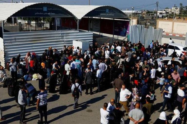 Multidão em pé aguarda na passagem de fronteira de Rafah com o Egito