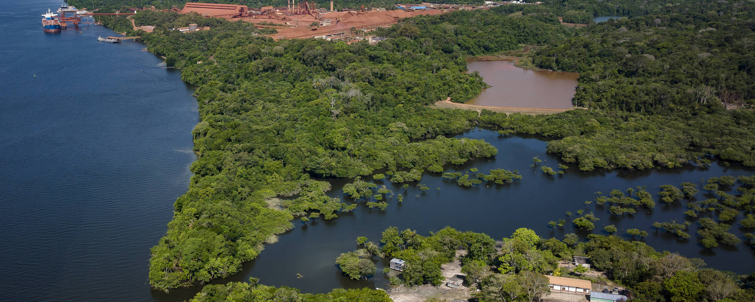 Vista aérea do quilombo (abaixo), a barragem de rejeitos da mineradora mais ao centro e o porto de carregamento de bauxita (acima).