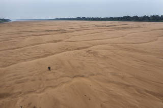 Pescador atravessa caminhando o leito seco do rio Solimões