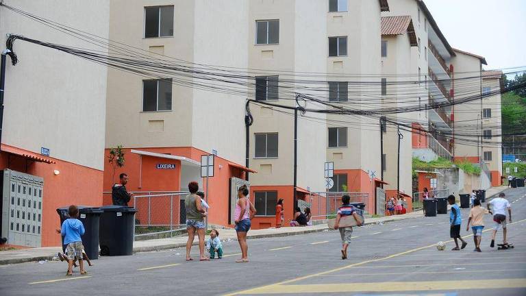 Pessoas caminham e crianças brincam próximas a edifícios do programa habitacional Minha Casa Minha Vida