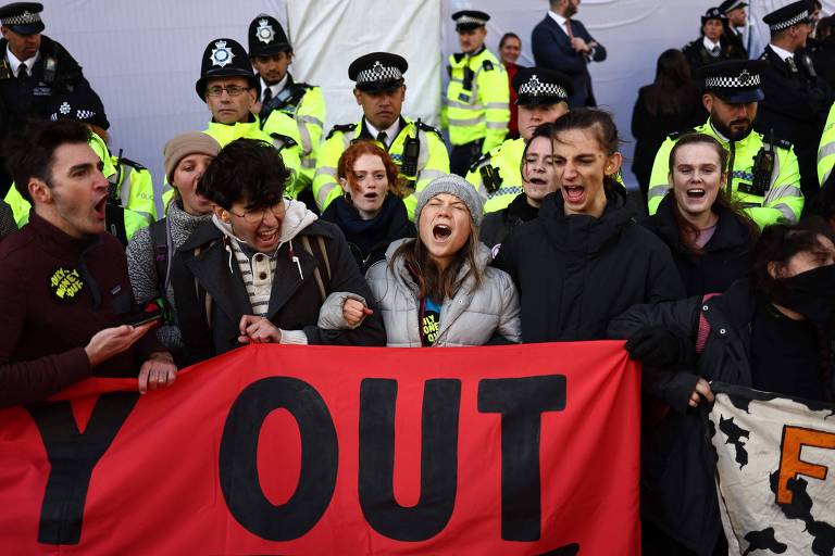 Grupo de jovens grita segurando um cartaz