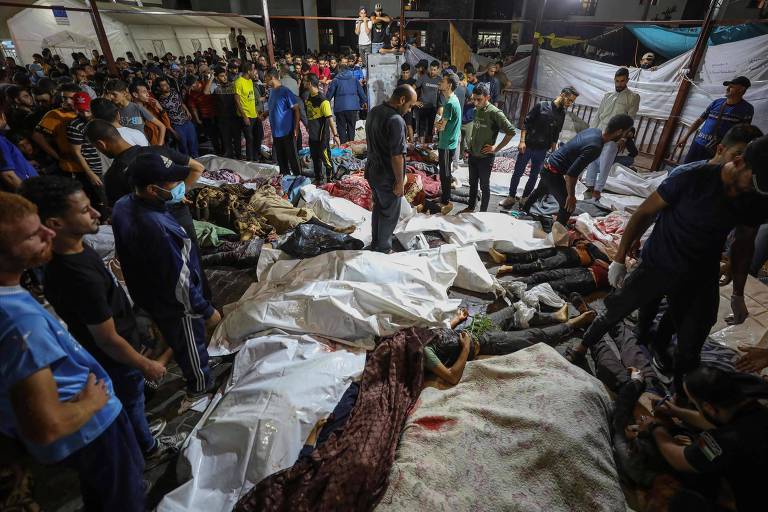 Moradores ao redor de corpos de pessoas mortas após ataque ao hospital al-Ahli Arab na cidade de Gaza