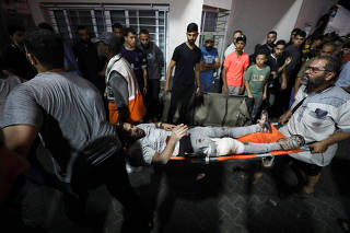 Injured people are assisted after Israeli air strike hit a hospital, according to Gaza Health Ministry
