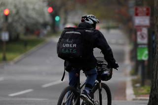 FILE PHOTO: An Uber Eats bicyclist makes a delivery during the coronavirus outbreak, in the U.S. Capitol Hill neighborhood in Washington