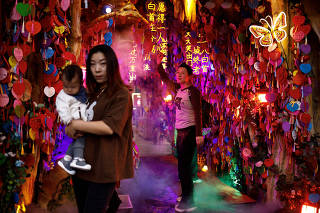 People pose for pictures at a tourism attraction in Beijing