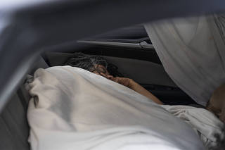Chrystal Audet sleeping in her car at a SafePark location, for people who are living out of their cars, at the Lake Washington United Methodist Church in Kirkland, Wash. on Aug. 28, 2023. (Ruth Fremson/The New York Times)