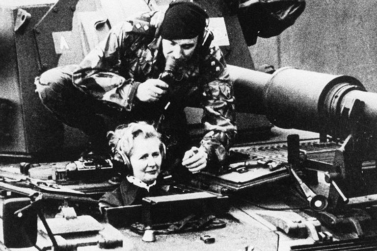 A primeira-ministra britânica Margaret Thatcher (1925-2013) passeando de tanque com soldado, em visita ao pelotão de seu país na Alemanha Ocidental, em 1987