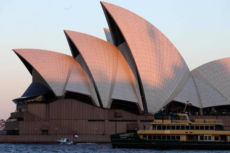 Pequena embarcação passa pela Ópera de Sydney, na Austrália, com bandeira da Palestina