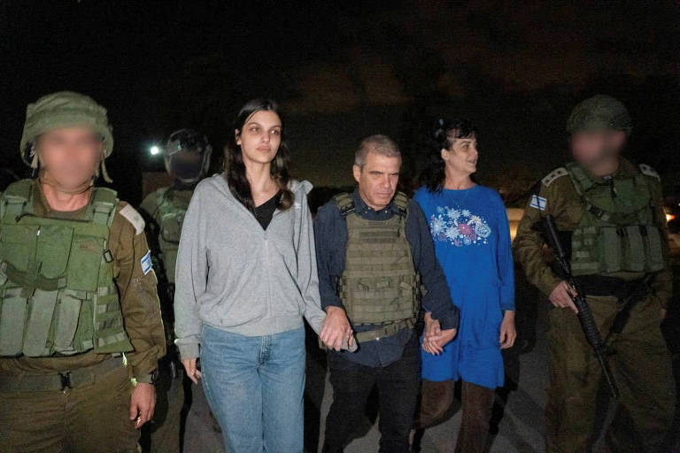 As cidadãs americanas Judith Raanan (de azul) e Natalie Raanan, após serem libertadas pelo Hamas, de mãos dadas com o brigadeiro-general israelense Gal Hirsch