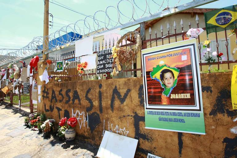 Imagem mostra flores e cartazes de protesto contra a morte do menino Joaquim em frente à casa onde ele morava, em Ribeirão Preto