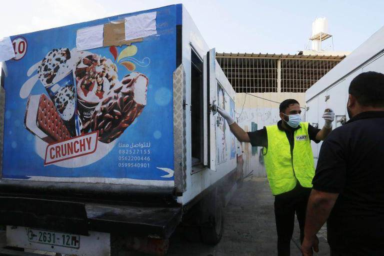 Policial usa caminhão de sorvete para colocar corpos no Hospital dos Mártires de Al Aqsa, na Faixa de Gaza
