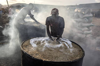 Laborers in Gombe, Nigeria, soak and heat rice to separate the grain from husks on Sept. 16, 2023.  (Finbarr OÕReilly/The New York Times)