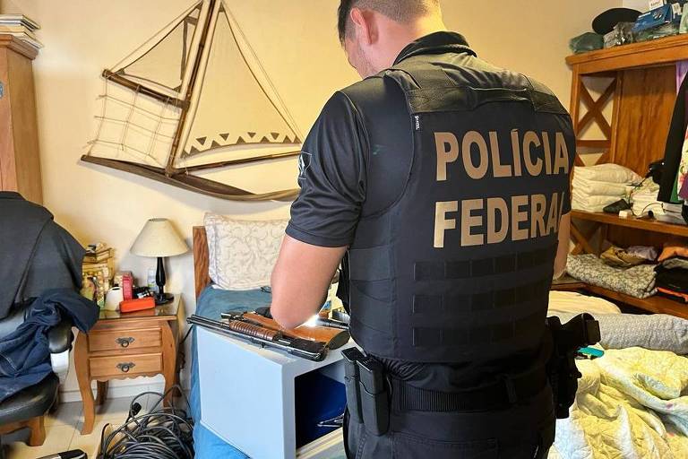 Policial federal de costas analisa documentos e materiais em endereço de investigado