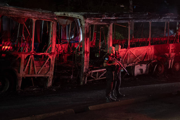 Carcaça de ônibus queimado é escoltada por dois policiais militares