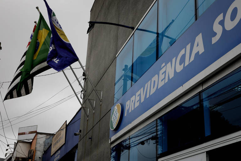 Bandeiras do Brasil, São Paulo e INSS em prédio com placa onde se lê Previdência Social