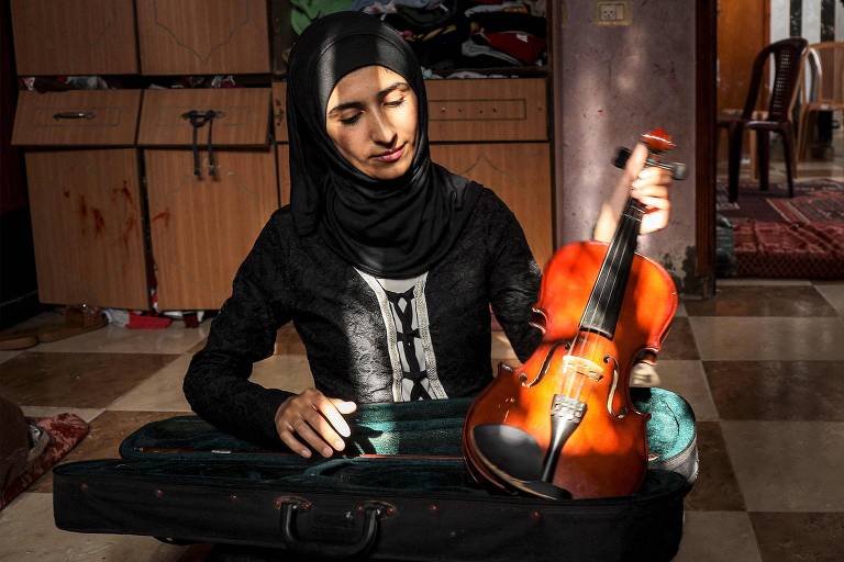 A musicista palestina Jawaher al-Aqraa segura seu violino em sua casa em Deir al-Balah, no centro da Faixa de Gaza