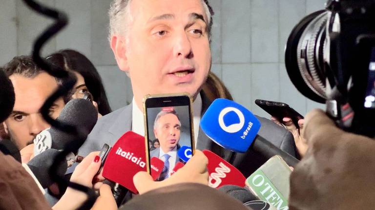 O presidente do Senado, Rodrigo Pacheco, fala com jornalistas. Ele está diante de microfones, câmeras e celulares