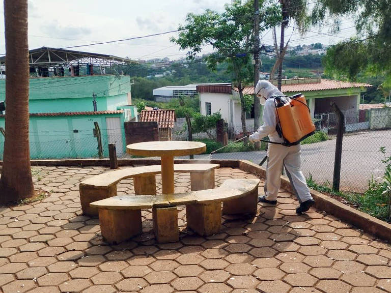 A foto mostra agente usando equipamento de desinfecção em escola municipal de São João del Rei.