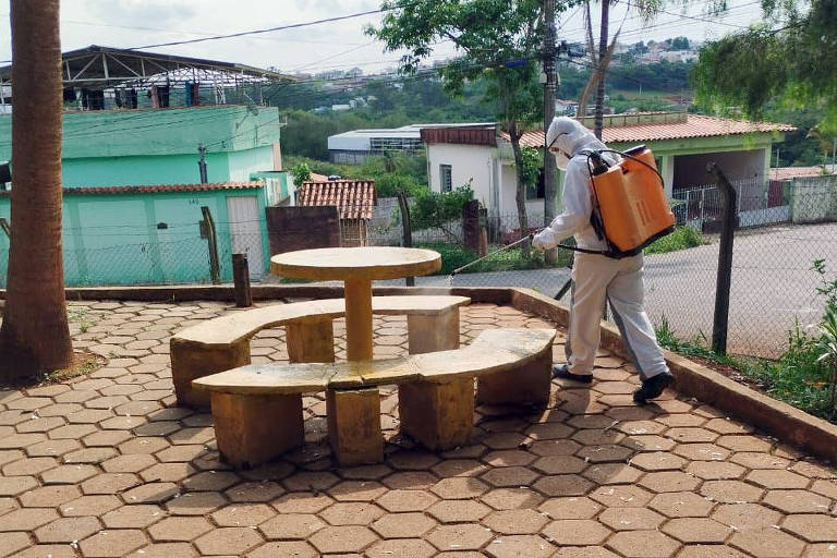 A foto mostra homem com equipamento nas costas atuando na desinfecção de escola em São João del Rei.