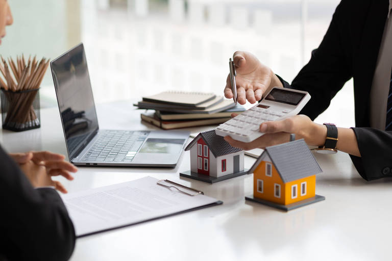 Agente imobiliário segurando uma calculadora, apresentando uma cotação de preço a um cliente para uma casa|