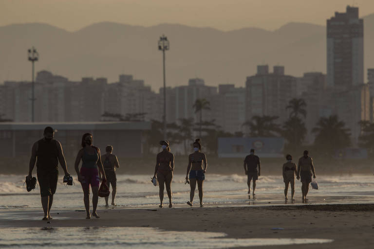 por do sol na praia com silhueta de pessoas caminhando na faixa de areia